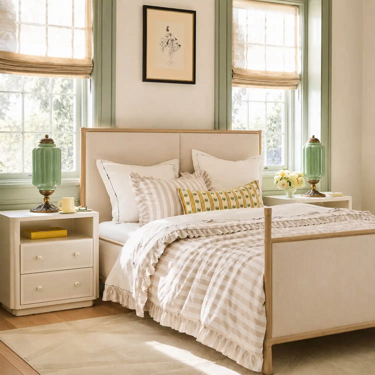 Neatly made bed with decorative pillows in a bright bedroom with two windows.