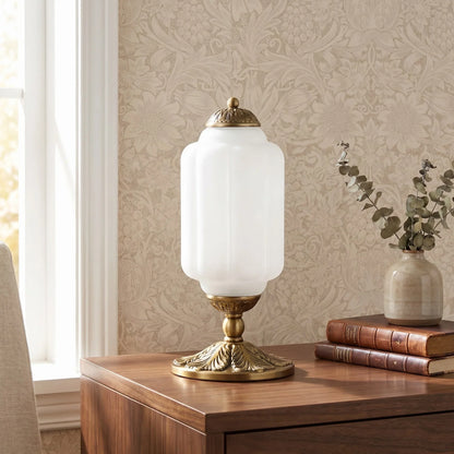 Decorative table lamp with white glass shade and gold base on a wooden surface.