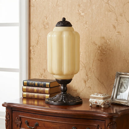 Decorative table lamp on a wooden surface with books and a photo frame in the background.
